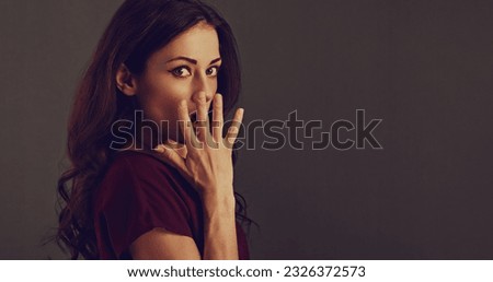 Beautiful excited surprising makeup woman with long brown healthy hair looking with open mouth and big eyes. Closeup portrait on grey studio background. Toned vintage color