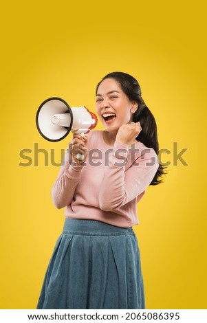 a beautiful excited woman shouting holding a megaphone and clenching hands