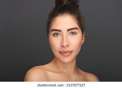 Beautiful exotic model with green eyes in beauty portrait. High fashion beauty and skin shoot in studio of latina or hispanic model with young and fresh skin. Shot on a gray background.