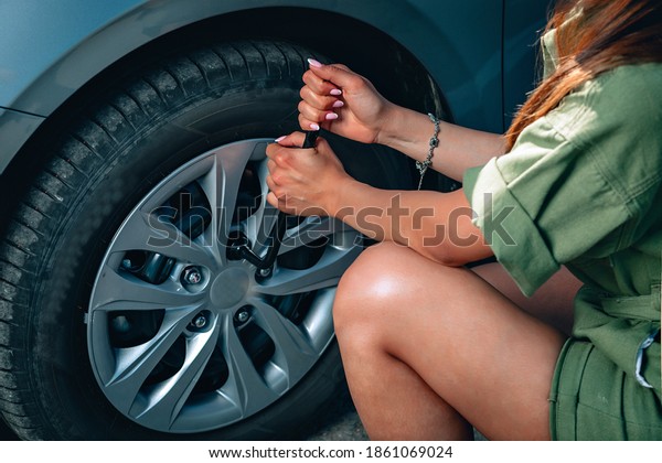 beautiful experienced woman\'s hands are\
fixing a wheel of the car by socket wrench, close\
up