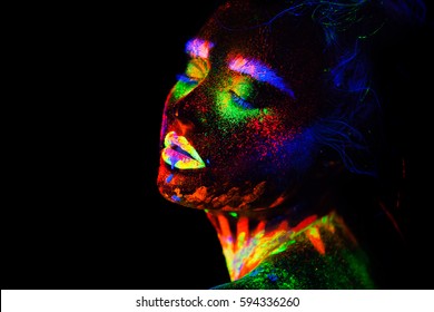 Beautiful extraterrestrial model woman in neon light. It is portrait of beautiful model with fluorescent make-up, Art design of female posing in UV with colorful make up. Isolated on black background
