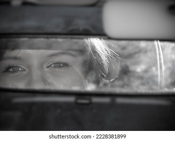 Beautiful eyes of a girl in the rearview mirror of a car. Black and white photo