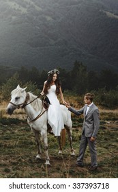 beautiful fabulous happy  bride riding a horse and stylish groom on the background of   the stunning mountains