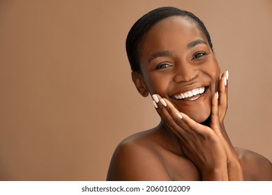 Beautiful face of mature smiling woman with clean fresh skin isolated against brown background. African middle aged woman touching cheeks and looking at camera. Mid adult black lady holding her cheeks