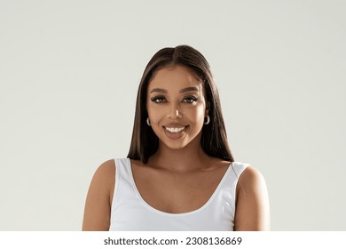 Beautiful face of an young happy model with dark eyes and amazing big smile. Woman wearing fashionable earrings looking at the camera. A lot of copy space. 