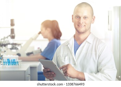 Beautiful Fair-haired Technologist With Clipboard And Pen In Hands Standing At Conveyor Belt And Controlling Production Process At Modern Soy Milk Factory, Portrait Shot