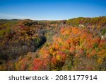 Beautiful Fall colours views of the Spencer Gorge along the Dundas Peak trail in Hamilton, Ontario, Canada. The sky is cloudless blue.