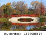 Beautiful fall landscape with a bridge in the city park. Scenic view with colored trees and bridge in sunlight reflected in the lake Mendota bay water. Tenney Park, Madison, Midwest USA, Wisconsin.
