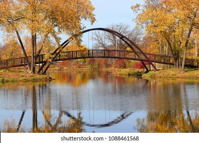 Beautiful Fall Landscape With A Bridge In The City Park. Colored Trees And Bridge In Sunlight Reflected In The Lake Mendota Bay Water. Tenney Park, Madison, Midwest USA, Wisconsin.