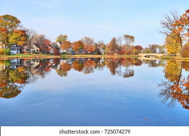 Beautiful Fall Landscape With A Bridge In The City Park.Small Neighborhood Homes Around A Pond, Colored Trees And Bridge In Sunlight Reflected In The Water. Tenney Park, Madison,Midwest USA,Wisconsin.