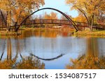 Beautiful fall landscape with stylish bridge in the city park. Scenic view with colored trees and bridge in sunlight reflected in the lake Mendota bay water. Tenney Park, Madison, Wisconsin, USA.