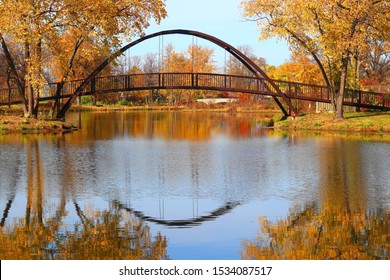 Beautiful Fall Landscape With Stylish Bridge In The City Park. Scenic View With Colored Trees And Bridge In Sunlight Reflected In The Lake Mendota Bay Water. Tenney Park, Madison, Wisconsin, USA.