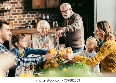 beautiful family clinking glasses of wine and juice on holiday dinner