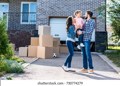beautiful family in front of new house with many boxes standing on pathway to garage