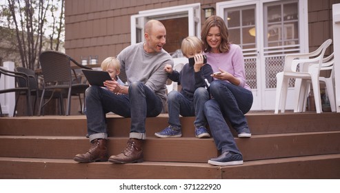 Beautiful Family Looking At Handheld Devices Outside.