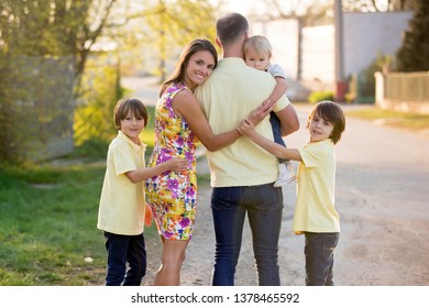 Beautiful Family, Mother, Father And Three Kids, Boys, Having Familly Outdoors Portrait Taken On A Sunny Spring Evening, Beautiful Blooming Garden, Sunset Time, Back Lit. Parents And Children Have Fun