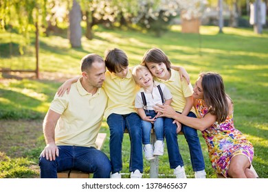 Beautiful Family, Mother, Father And Three Kids, Boys, Having Familly Outdoors Portrait Taken On A Sunny Spring Evening, Beautiful Blooming Garden, Sunset Time, Back Lit. Parents And Children Have Fun