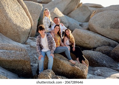 A Beautiful Family On A Beach. Golden Light With Rocks. A Loving Family With Teenager Children. 