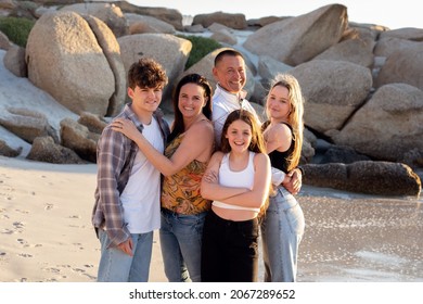 A Beautiful Family On A Beach. Golden Light With Rocks. A Loving Family With Teenager Children. 