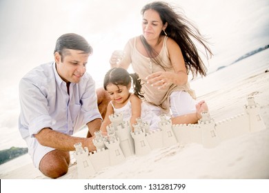 Beautiful Family On Holidays Building Sand Castles At The Beach