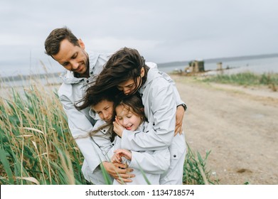 Beautiful Family Portrait Dressed In Raincoat Near The Lake