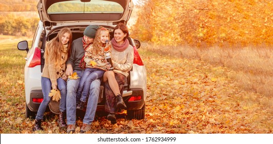 Beautiful Family Resting In Car Trunk On Autumn Background