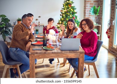 Beautiful family smiling happy and confident. Eating roasted turkey make videocall using laptop celebrating christmas at home - Powered by Shutterstock