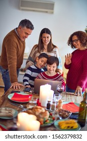 Beautiful Family Smiling Happy And Confident. Eating Roasted Turkey Make Videocall Using Laptop Celebrating Christmas At Home