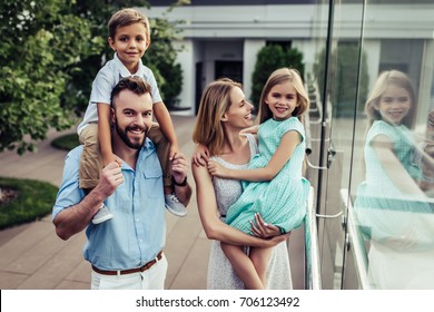 Beautiful Family Is Spending Time Together Outside. Parents With Their Children On A Roof Terrace With View On A City. Mom And Dad Are Having Fun With Their Charming Daughter And Son.