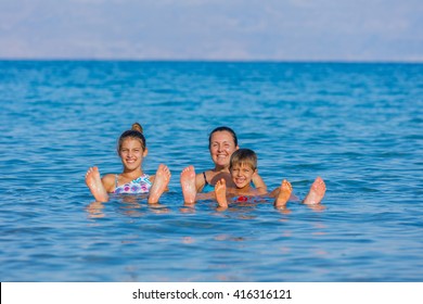 Beautiful Family Of Three Floating In The Waters Of The Dead Sea, Israel