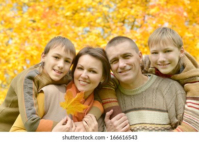 Beautiful Family Together For A Walk During The Fall Of The Leaves In The Park