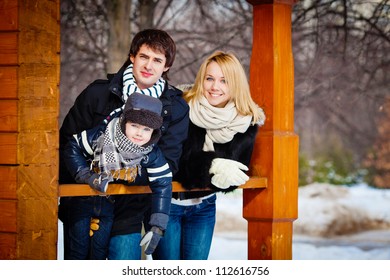 Beautiful Family In Warm Clothes Standing On The Porch Of His House In Winter, Horizontal Photo