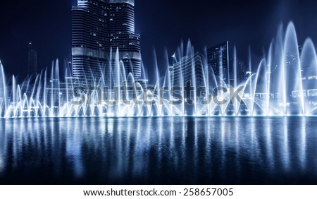 Beautiful famous fountain in Dubai at night, romantic music, water dance, blue lights, luxury resort, evening cityscape