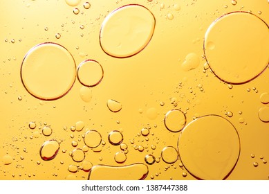 Beautiful and fantastic macro photo of water droplets in oil with a yellow background.