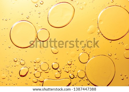 Beautiful and fantastic macro photo of water droplets in oil with a yellow background.