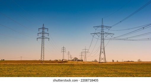 Beautiful farm landscape and high voltage power lines pylons in Germany at Autumn colors during sunset with blue sky. Concept of energy supply and energy crisis - Powered by Shutterstock