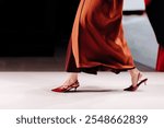Beautiful fashion details of long warm brown orange coat and red high heels, women