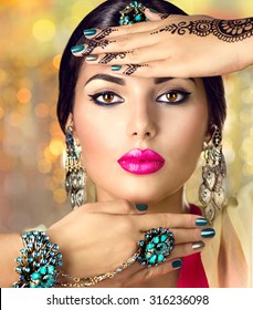 Beautiful fashion Indian woman portrait with oriental accessories- earrings, bracelets and rings. Indian girl with black henna tattoos and beauty jewels. Hindu model with perfect make-up. India