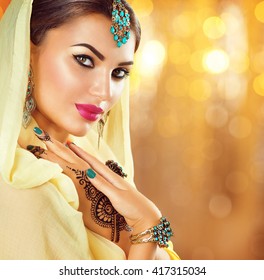 Beautiful fashion Indian woman portrait with oriental accessories- earrings, bracelets and rings. Arabic girl with black henna tattoos and beauty jewels. Hindu model with perfect make-up. India
