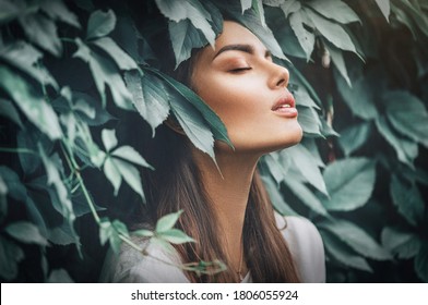 Beautiful fashion model girl enjoying nature, breathing fresh air in summer garden over Green leaves background. Harmony concept
