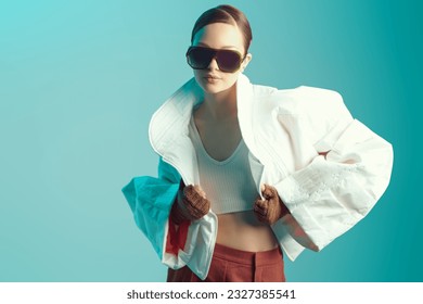 Beautiful fashion model girl posing in designer clothes on blue studio background with place for text. Fashion haute couture collection. Wide free forms in clothes, oversized style. 