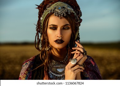 Beautiful fashion model posing in boho style clothes in the rays of the sunset. Outdoor fashion.