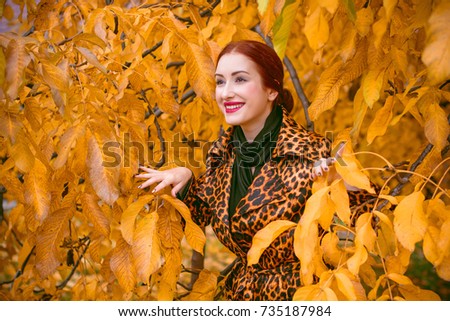 Beautiful fashion woman in animal print coat posing for the camera. Sweet vintage fashionable lady wearing a retro leopard coat and scarf, casual vintage style in everyday life, autumn garden