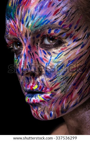 Beautiful fashion woman with bright color face art and body art. Painted lines on face. Creative portrait close up.