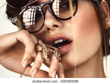 Beautiful fashion woman with creative make-up and hairstyle wearing glasses and jewelry. The beauty of the face. Photos shot in the studio.