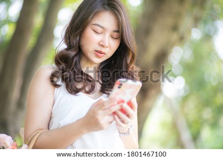 Beautiful fashion women use smartphone in green city park nature background