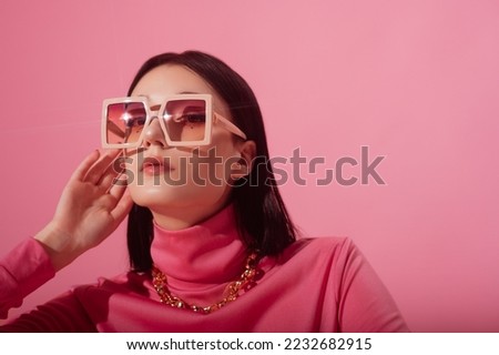 Beautiful fashionable confident woman wearing trendy pink butterfly square sunglasses, chunky chain necklace, stylish turtleneck top. Close up studio portrait. Copy, empty space for text