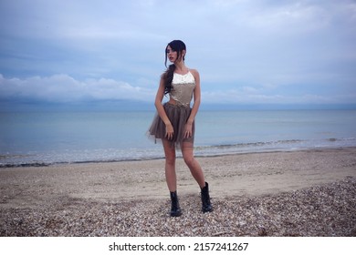 Beautiful Fashionable Girl Stands On The Seashore Of The Sia In A Chiffon Skirt And A Shiny  Shirt At The Watter