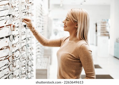 Beautiful and fashionable woman choosing eyeglasses frame in modern optical store. - Powered by Shutterstock