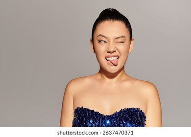 A beautiful, fashionable woman showcases her playful side, winking and sticking out her tongue.